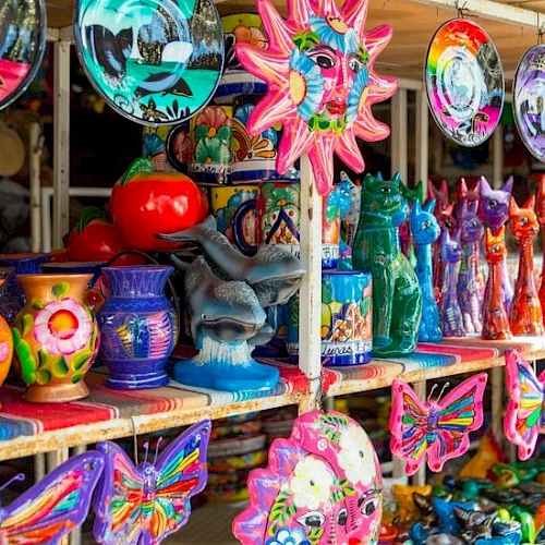 Colorful carnival souvenirs on display: wind chimes, ceramic bowls, dragon figurines, butterfly wind sculptures, and dragon boats.